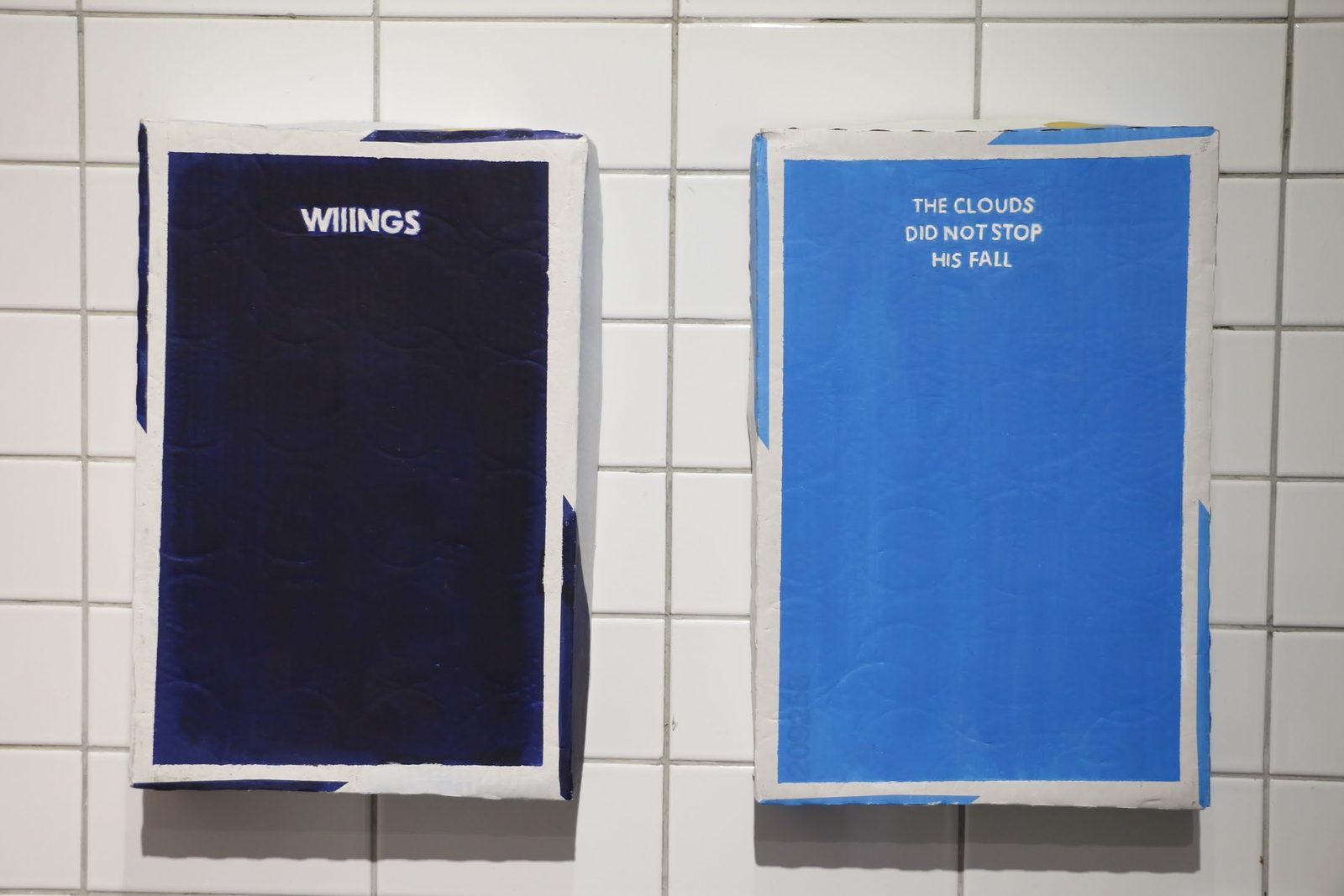 Two painted cartons on a tiled wall