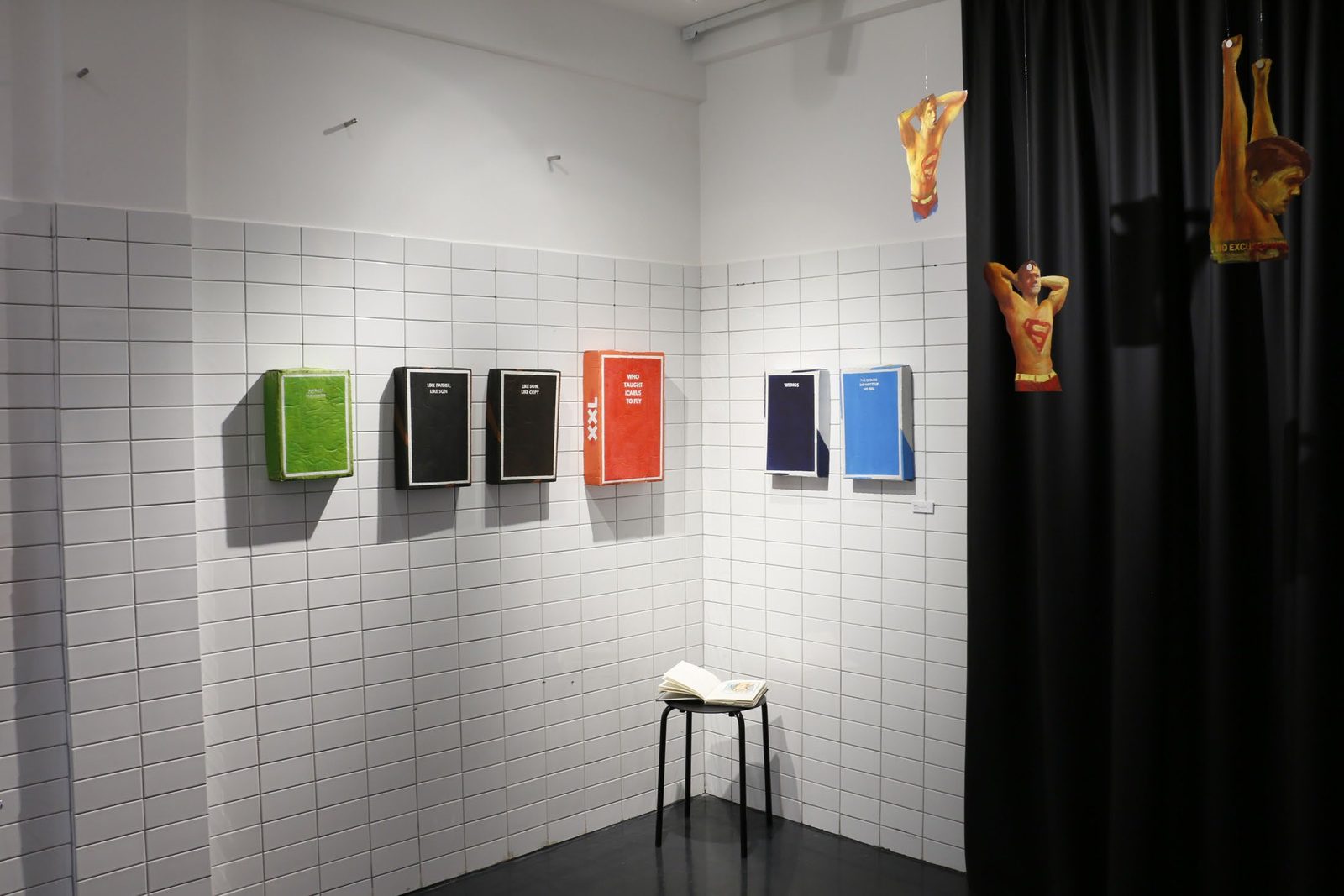 Installation view with cartons on a tiled wall and a hanging cutout